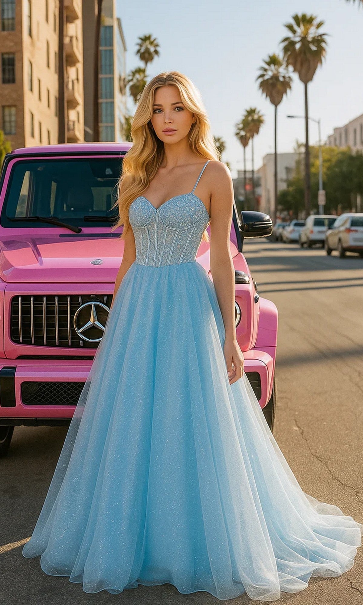 A woman in a Portia and Scarlett XO163 light blue prom ball gown with an embellished bodice stands before a parked pink Mercedes SUV on a sunny city street lined with palm trees.